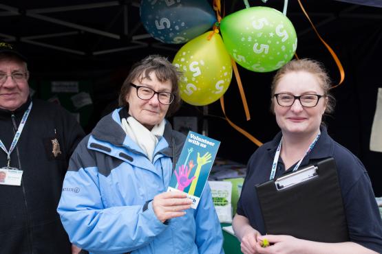 A Healthwatch employee at a community event and a member of the public holding a leaflet
