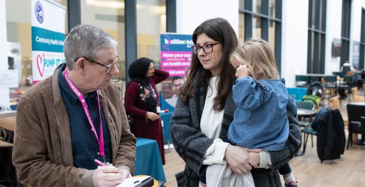 Volunteer talking to woman with little girl