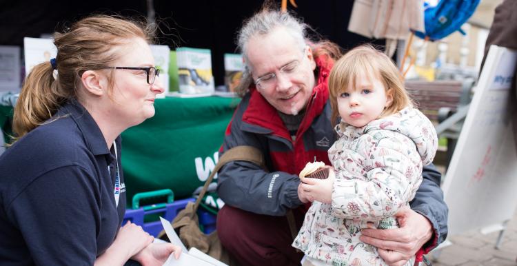 Healthwatch volunteer speaking to a grandparent and child at an event