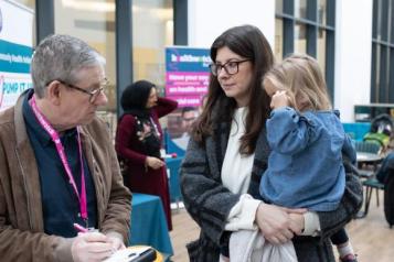 Volunteer talking to woman with little girl