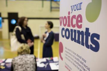 Women talking with Healthwatch 'your voice counts' sign in front at event