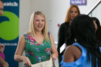 Woman smiling at a Healthwatch event, picking up promotional materials
