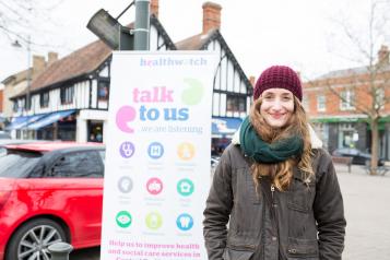 Young woman in front of Healthwatch sign