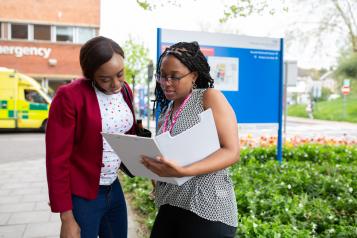 Women looking at file in front of hospital sign