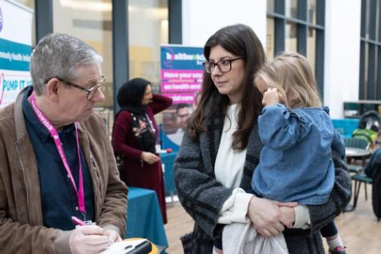 Volunteer talking to woman with little girl